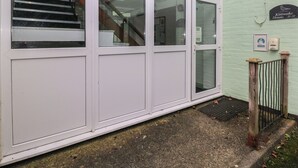 A building with a white exterior, a staircase leading to an upper floor, and a sign indicating the name and address. - Kittiwake, Apartment 22 (Haverfordwest)