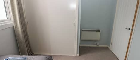 Un dormitorio con dos camas, una ventana con cortinas, un radiador y una puerta.