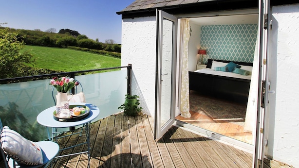 A balcony with a glass table, chairs, and a small garden. - Goleufryn (Beaumaris)