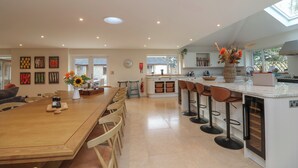 A spacious kitchen with a central island, bar stools, and a dining area. - Blossom Hill (Witney)