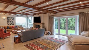 A spacious living room with a fireplace, a television, and a large window offering a view of the outdoors. - Blossom Hill (Witney)