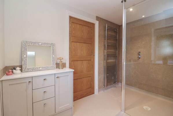 Une salle de bain avec un meuble-lavabo blanc, une porte en bois et une cabine de douche en verre.