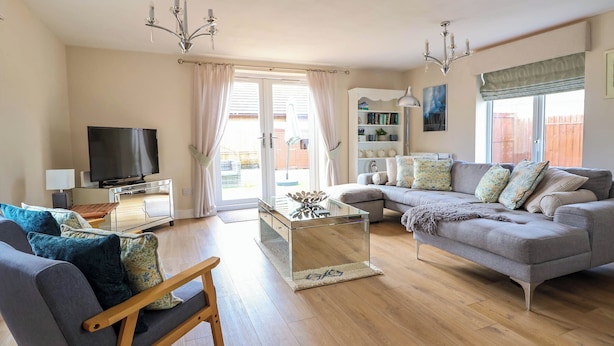 A living room with a TV, sofa, and wooden chair. - Brimrod (Holywell)
