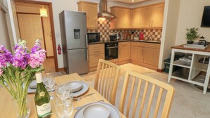A compact kitchen with wooden cabinets, a stainless steel refrigerator, and a microwave. - Medina by The Solent (Cowes)