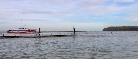 A calm waterfront with a Red Jet boat docked at a pier.