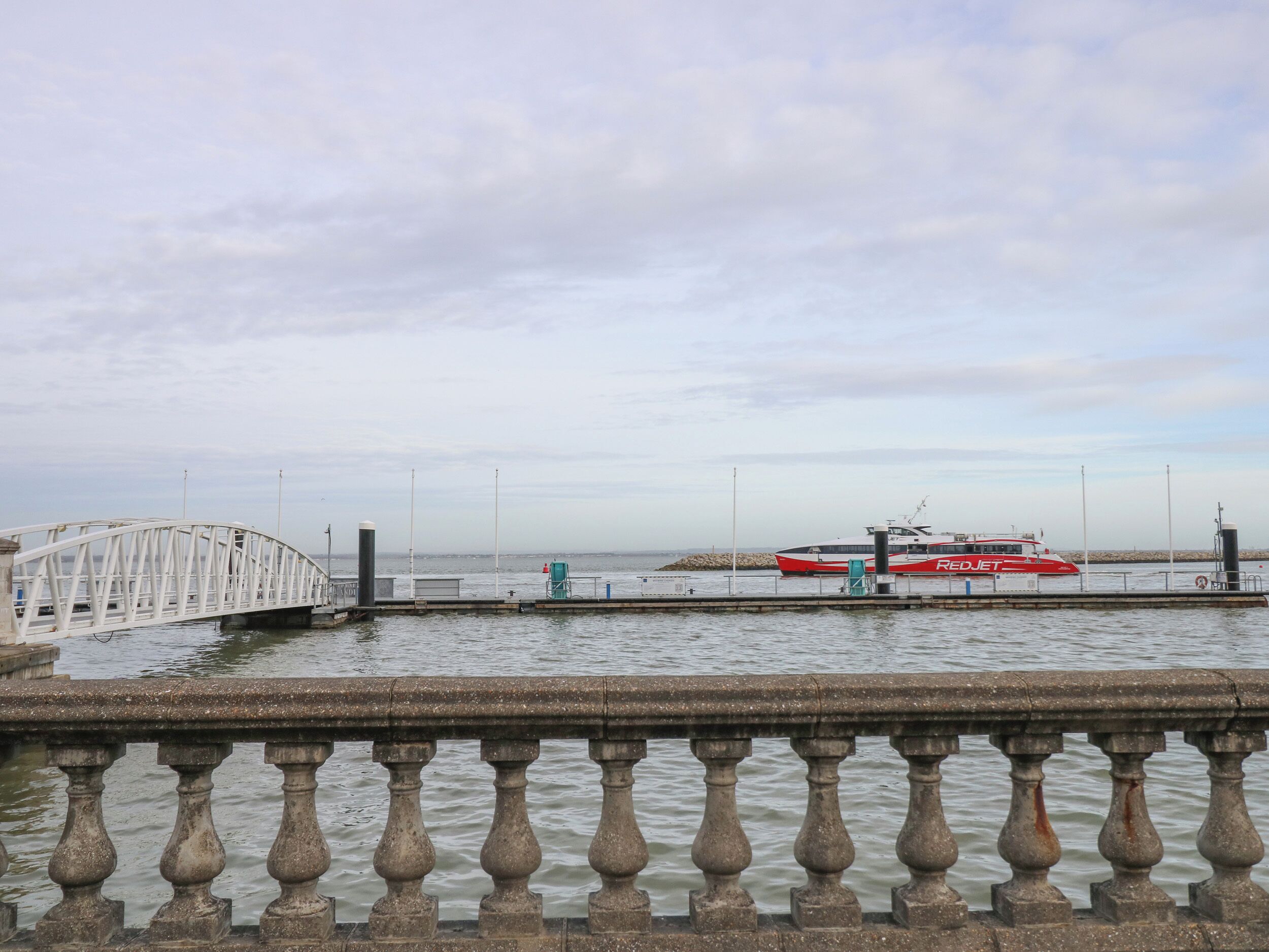 Un puente con barandilla blanca y un barco amarrado en un muelle.