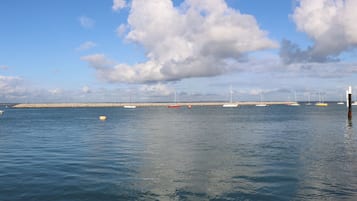 Ein ruhiger Hafen mit Booten, einem Wellenbrecher und blauem Himmel.