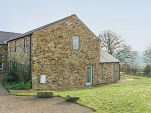 Un bâtiment en pierre avec un toit en pente, une petite dépendance attenante et une allée pavée.