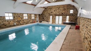 Una piscina interior con paredes de piedra y techo alto.