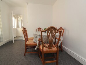 A dining area with a table and four chairs, a door leading to another room, and a carpeted floor. - 21 Eaves Street (Blackpool)