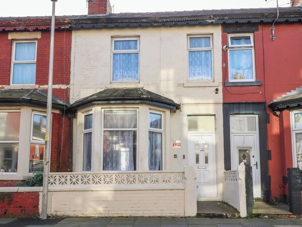A row of terraced houses with bay windows, a white door, and a red door. - 21 Eaves Street (Blackpool)