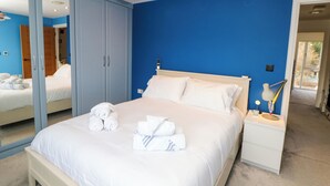 Un dormitorio moderno con una cama grande, una mesita de noche con lámpara y un armario.