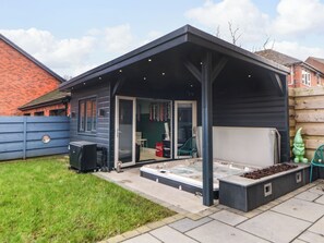 A modern outdoor patio with a hot tub, a glass door entrance, and a covered seating area. - 4 Rockcliffe Grange (Mansfield)