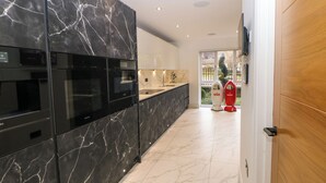 Una cocina moderna con armarios de mármol negro, encimera blanca y vistas al exterior a través de un ventanal.