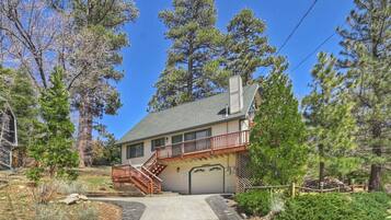 Set amidst mature pine trees, this two-story house offers a serene retreat with a covered garage and a balcony overlooking the surrounding woods.