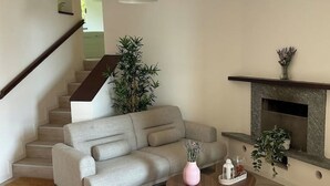 A living room with a grey sofa, a small round table, a pink vase, and a fireplace. - LAKE AND MOUNTAIN (Civenna)