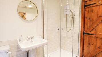 Un bagno con doccia vetro, lavandino bianco e porta in legno.