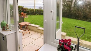 Una veranda con vista su un giardino, un tavolo di legno e una piccola casa in miniatura sul davanzale.
