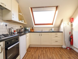 A kitchen with white cabinets, a black countertop, a gas stove, and a skylight.