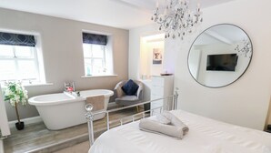 Un dormitorio moderno con una cama grande, una bañera y una silla.