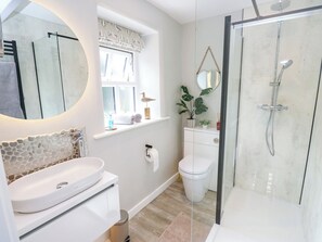 A modern bathroom with a glass shower enclosure, a white sink, and a toilet. - Thimble Cottage (Keighley)
