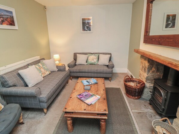 A cozy living room with a sofa, a coffee table, a fireplace, and a stone wall.