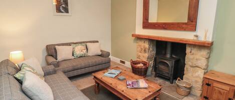 A cozy living room with a sofa, a coffee table, a fireplace, and a mirror on the wall.