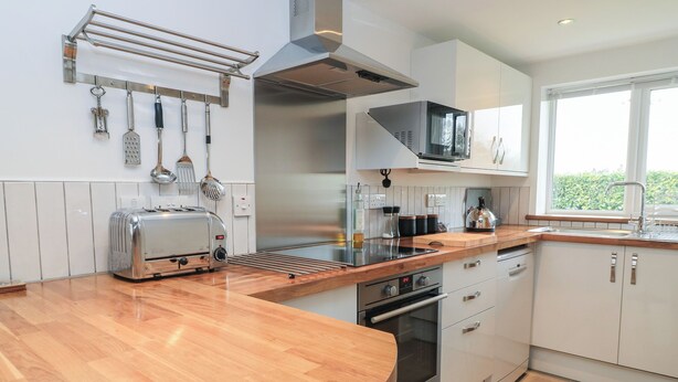 Eine moderne Küche mit Holzausziehtisch, Edelstahlgeräten und einem Fenster, das natürliches Licht hereinlässt.