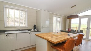 Una cocina moderna con una isla de madera, taburetes de bar y un comedor con vistas.