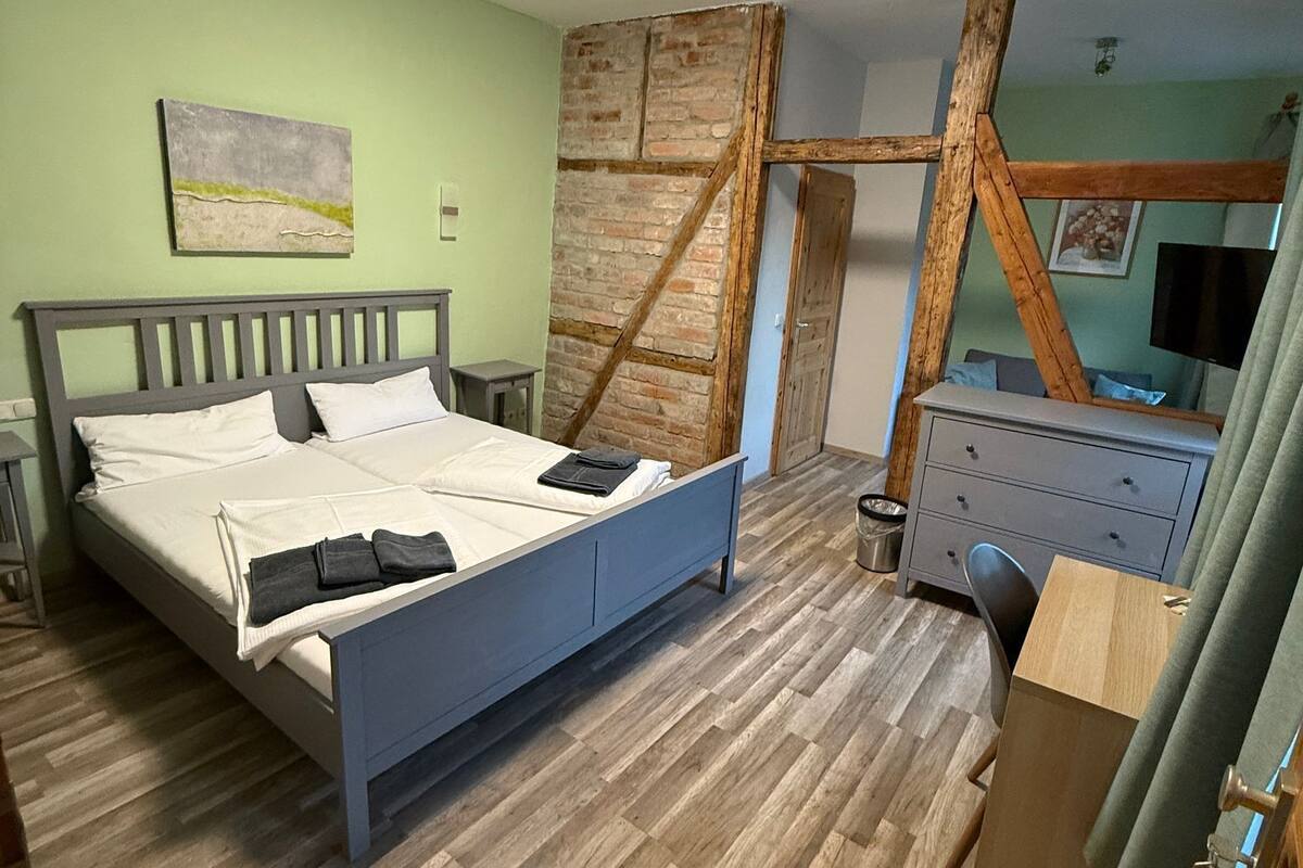 A bedroom with a bed, a dresser, a desk, and a television.