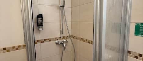 Un petit espace douche fermé, équipé d’un pommeau de douche à main et d’un robinet à main.