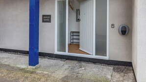 Een gebouwtoegang met een 'Groves House' bord, een glazen deur, een metalen plank en een beveiligingsapparaat.