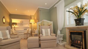 A cozy living room with a fireplace, comfortable seating, and a decorative plant. - Tree Tops (Broadway)