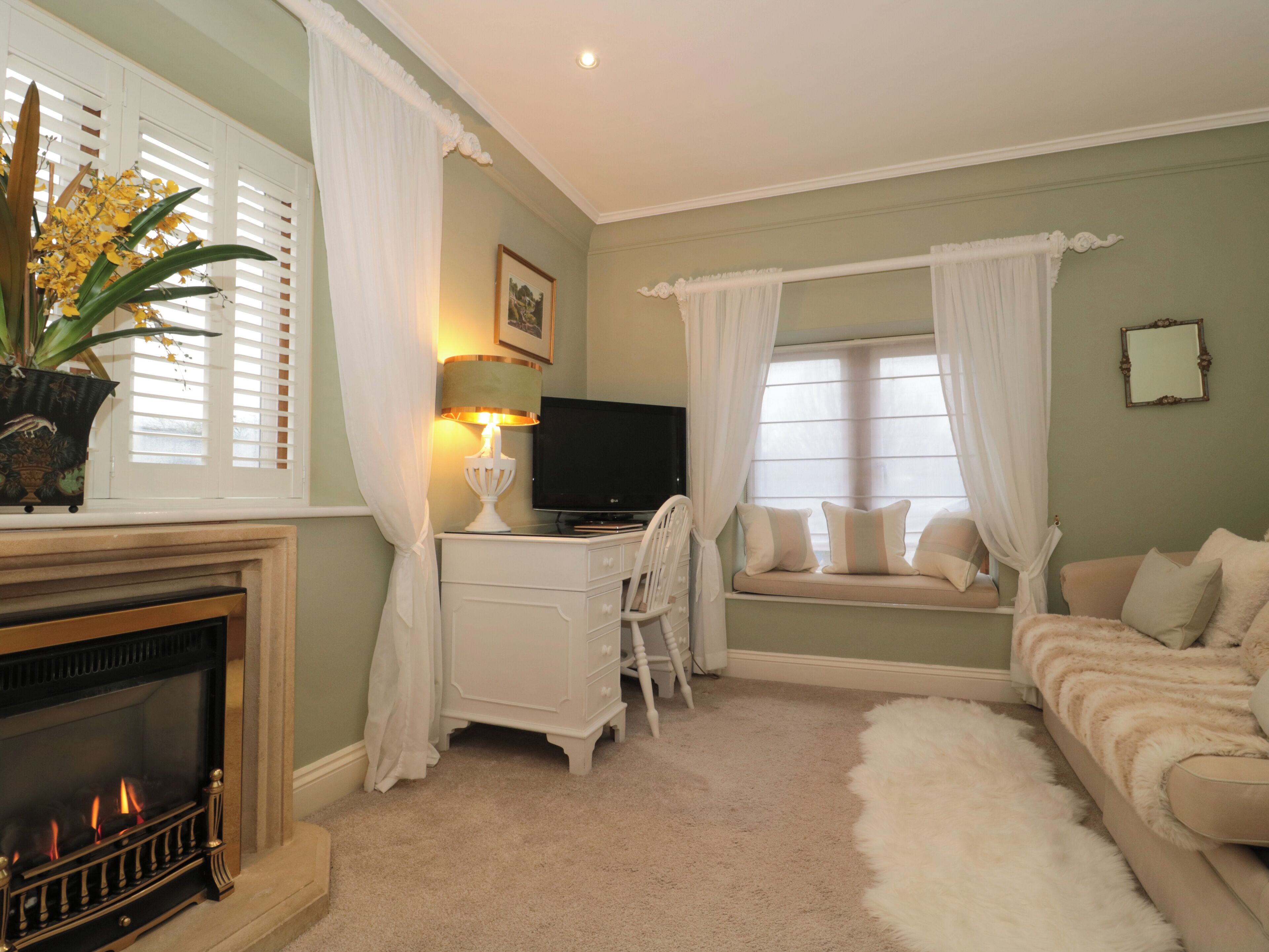 A cozy living room with a fireplace, a television, and a comfortable seating area with a sofa and a cushioned bench.