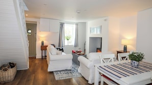 A modern, well-lit room with a bed, a small table, and a chair. There is a window with curtains, a fireplace, and a wall-mounted TV. - Cwrt (Llanfairpwllgwyngyll)