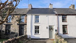 A two-story stone house with a white exterior, a brick roof, and a small front garden. - Cwrt (Llanfairpwllgwyngyll)