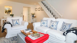 A living room with white furniture, a wooden coffee table, and a staircase. - Cwrt (Llanfairpwllgwyngyll)