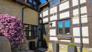 A traditional half-timbered building with a brick pathway leading to the entrance. - Clandyke Cottage (Ludlow)