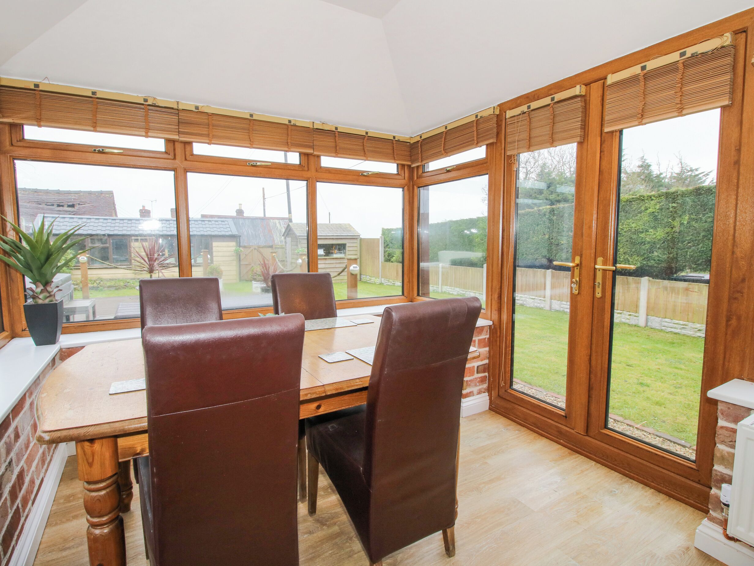 A dining area with a table and chairs, large windows, and a view of the backyard.