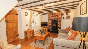 A cozy living room with a fireplace, wooden furniture, and a television. - Clandyke Cottage (Ludlow)