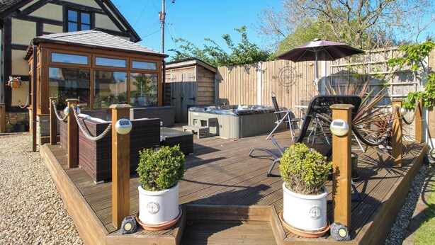 A wooden deck with hot tubs, a barbecue area, and potted plants. - Clandyke Cottage (Ludlow)