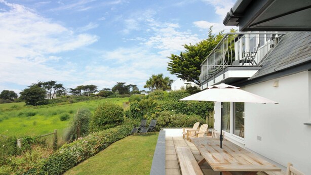 Une terrasse avec des bancs en bois et une table, offrant une vue sur un paysage verdoyant et luxuriant.