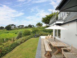 Un patio con bancos de madera y una mesa, con vistas a un paisaje verde y exuberante.