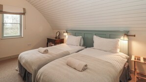 Un dormitorio con dos camas, una ventana, una mesita de noche y una lámpara.