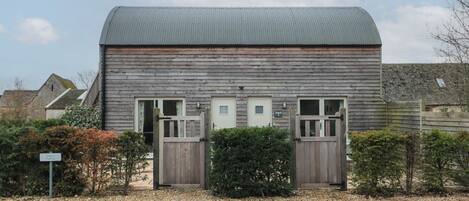 A wooden building with a metal roof, two doors, and a gravel driveway.