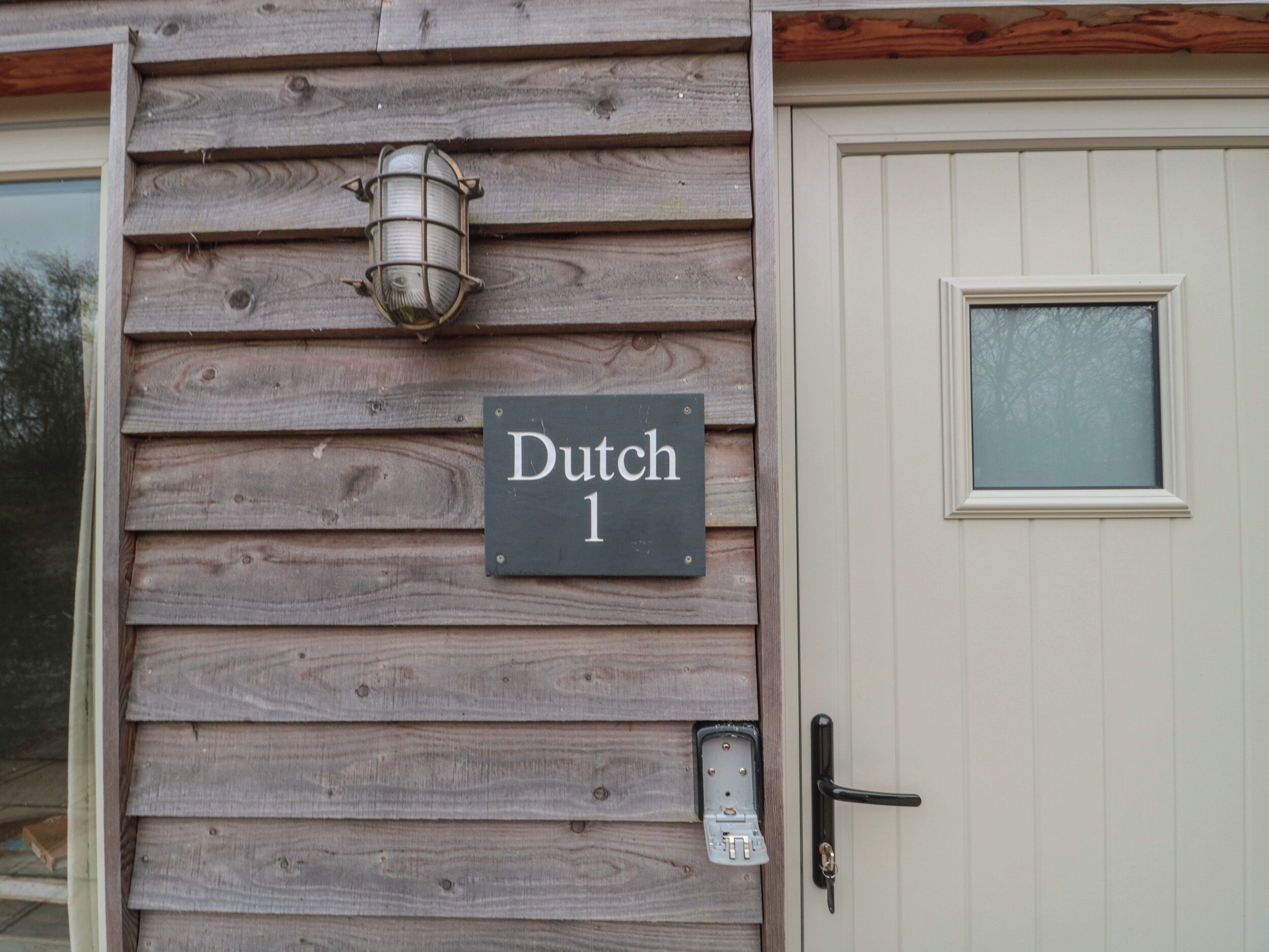 Un mur extérieur en bois, sur lequel est apposée une enseigne indiquant « Dutch 1 », et une porte dotée d’une fenêtre.
