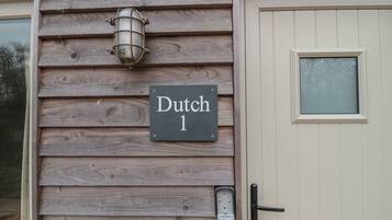 Un mur extérieur en bois, sur lequel est apposée une enseigne indiquant « Dutch 1 », et une porte dotée d’une fenêtre.