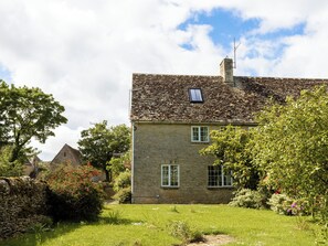 A stone house with a tiled roof, a chimney, and a small window.