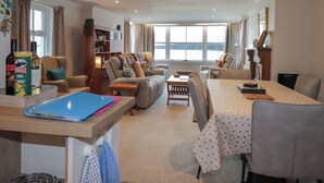 A spacious living area with a sofa set, a dining table, and a bookshelf.