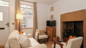 Una sala de estar con sofá, sillones, televisor, chimenea y una ventana con cortinas.